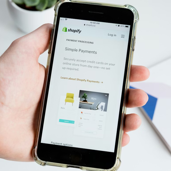 Customer holding an iphone with a Shopify site on it